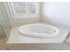 Bright bathroom with an oval soaking tub with jets and tiled surround next to a window with shutters at 1140 Matheson Way, Alpharetta, GA 30022