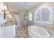Luxury bathroom with a soaking tub, double vanity, glass shower, tiled floor, and arched window at 1140 Matheson Way, Alpharetta, GA 30022