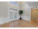 Spacious living room with hardwood floors, wainscoting, a tall plant, and double doors with shuttered windows at 1140 Matheson Way, Alpharetta, GA 30022