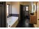 A modern bathroom features a soaking tub, wood vanities, vessel sink and dark marble floors at 3065 Kings Nw Dr, Kennesaw, GA 30144