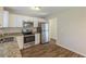 Well-lit kitchen with stainless steel appliances, granite countertops, and white cabinetry and wood flooring at 1526 Colony East Cir, Stone Mountain, GA 30083