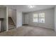 Spacious living room with a staircase, large window, and neutral color palette at 4342 Lincolndale Dr, Ellenwood, GA 30294