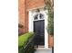 Charming brick townhouse features a black front door, complemented by lush greenery and an elegant light fixture at 774 Piedmont Ne Ave # 2A, Atlanta, GA 30308