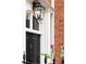 Close-up of a black front door with an elegant light fixture, brick facade, and manicured landscaping at 774 Piedmont Ne Ave # 2A, Atlanta, GA 30308