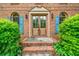 Inviting brick entryway with a wood double door, flanked by windows and trimmed with vibrant green bushes at 505 Summer Ter, Woodstock, GA 30189