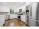 Modern kitchen features stainless steel appliances, sleek white cabinetry, and hardwood floors with island at 505 Summer Ter, Woodstock, GA 30189