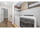 Well organized laundry room featuring new front loading machines, wood shelving and a doorway leading to stairs at 505 Summer Ter, Woodstock, GA 30189