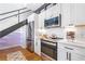 Modern kitchen with white cabinets, stainless steel appliances, subway tile backsplash, and hardwood floors near black staircase at 260 18Th Nw St # 10202, Atlanta, GA 30363