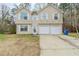 Beige two-story home with a two-car garage and front lawn at 445 Skif Pond Ct, Atlanta, GA 30349
