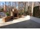 Outdoor backyard fireplace with stone accents, complemented by manicured plants and a peaceful, wooded backdrop at 4960 Trevino Cir, Duluth, GA 30096