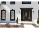 Close-up of the front door with decorative glass, sidelights, and black trim with manicured landscaping at 4960 Trevino Cir, Duluth, GA 30096