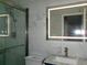 Updated bathroom featuring glass shower, illuminated mirror, marble-look tile, and stylish blue vanity at 6051 Wintergreen Rd, Norcross, GA 30093