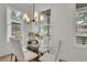 Bright dining room with a glass table, white chairs, and a modern light fixture with large windows at 826 Gaston Street Sw, Atlanta, GA 30310