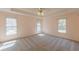 Spacious main bedroom with neutral carpet, a ceiling fan, and natural light from the three windows at 110 Eastfield Ct, Mcdonough, GA 30252