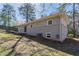 A home’s side and backyard features a brick foundation and an ample, tree-lined lawn perfect for outdoor activities at 1584 Belva Ave, Decatur, GA 30032