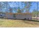 A spacious backyard features a grey, brick-bottomed home with a pair of black double doors and an ample lawn with sparse grass at 1584 Belva Ave, Decatur, GA 30032