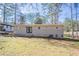 A spacious backyard features a grey, brick-bottomed home with a pair of black double doors and an ample lawn with sparse grass at 1584 Belva Ave, Decatur, GA 30032