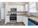 Updated kitchen features stainless steel appliances, granite countertops, and white cabinetry at 1584 Belva Ave, Decatur, GA 30032