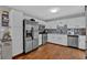 Well-lit kitchen with white cabinetry, stainless steel appliances, stylish backsplash and wood floors at 127 Hyde Way, Dallas, GA 30157