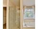 Bathroom featuring glass shower, soaking tub, and a window with natural light at 2697 Links Overlook Drive Dr, Dacula, GA 30019