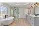 Bright bathroom featuring a soaking tub, dual sinks, modern fixtures, and wood flooring at 2063 Windermere Xing, Cumming, GA 30041