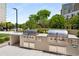 A modern outdoor grilling area with stainless steel appliances, countertop space, and lush landscaping at 2660 Peachtree Nw Rd # 14D, Atlanta, GA 30305