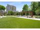 An outdoor lawn area with seating under a pergola and manicured green space in front of a tall residential building at 2660 Peachtree Nw Rd # 14D, Atlanta, GA 30305