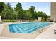 A large outdoor pool with lounge chairs and shaded seating area, surrounded by lush trees and well maintained landscaping at 2660 Peachtree Nw Rd # 14D, Atlanta, GA 30305