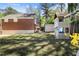 Backyard featuring brick home, play structure, shed, and lush greenery at 1265 Oldfield Rd, Decatur, GA 30030