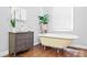 Comfortable bathroom with a classic clawfoot tub, dresser, and a window with blinds at 1265 Oldfield Rd, Decatur, GA 30030