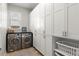 Bright laundry room with stainless steel washer and dryer, and built-in storage cabinets at 2046 Chambord Way, Snellville, GA 30078