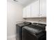 Compact laundry room with modern front-loading washer and dryer beneath white upper cabinets at 1564 Spring Se St, Smyrna, GA 30080