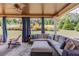 Covered outdoor patio with comfortable seating, ceiling fan, stone floor and view of landscaped backyard at 1433 Henderson Ridge Ln, Loganville, GA 30052