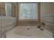 Soaking tub with tile surround and large window, perfect for relaxation and natural light at 117 Jacobs Ln, Loganville, GA 30052