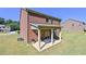 Back exterior view of the brick house featuring a covered patio, a lush green lawn, and blue skies at 1468 Harlequin Way, Stockbridge, GA 30281