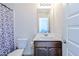 Cozy bathroom features a toilet, shower with patterned curtain, and a vanity with dark wood cabinets at 1468 Harlequin Way, Stockbridge, GA 30281