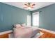 A cozy bedroom with a ceiling fan, pale gray bedding, hardwood floors, and blue walls at 3065 Park St, East Point, GA 30344