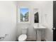 Bright half-bathroom featuring a sleek pedestal sink, modern fixtures, and a window with natural light at 1098 Wedgewood Nw Dr, Atlanta, GA 30318