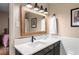 Bathroom with black fixtures, neutral walls, framed mirror with lighting above a white countertop with black cabinets at 2574 Sugarplum Ne Ct, Atlanta, GA 30345