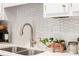 Close-up of a kitchen sink with stainless steel faucet, white counters, backsplash, and modern fixtures at 2574 Sugarplum Ne Ct, Atlanta, GA 30345