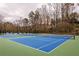 Aerial view of blue and green tennis courts surrounded by tall trees in the community at 2574 Sugarplum Ne Ct, Atlanta, GA 30345