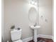 Powder room with pedestal sink, oval mirror, and a decorative plant on the back of the toilet at 4205 Idlewood Dr, Cumming, GA 30040