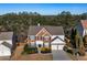 Aerial view of a two-story brick home with an attached garage in a wooded neighborhood at 3321 Spindletop Nw Dr, Kennesaw, GA 30144