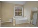 Bathroom featuring a soaking tub under a window and a neutral-toned color scheme at 1050 Westwell Run, Alpharetta, GA 30022
