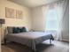 A well-lit bedroom with neutral walls, grey bedding, and deer-themed artwork above the bed at 1908 Stanton Rd, East Point, GA 30344