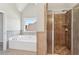 Bathroom featuring a soaking tub under a window and a shower with bronze colored tile at 70 Wentworth Ln, Villa Rica, GA 30180
