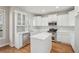 Well-lit kitchen boasts stainless steel appliances, white cabinetry, an island, hardwood floors, and natural light at 70 Wentworth Ln, Villa Rica, GA 30180