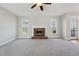 Open living room with stone fireplace, ceiling fan, plush carpet, and natural light from the exterior door and windows at 70 Wentworth Ln, Villa Rica, GA 30180