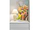 Bedroom staging with colorful floral paintings, and a white lamp sitting on a white dresser at 942 Byron Sw Dr, Atlanta, GA 30310