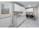 Well-lit laundry room with white cabinets, stainless steel washer and dryer, and utility sink at 2914 Stanway Ave, Douglasville, GA 30135
